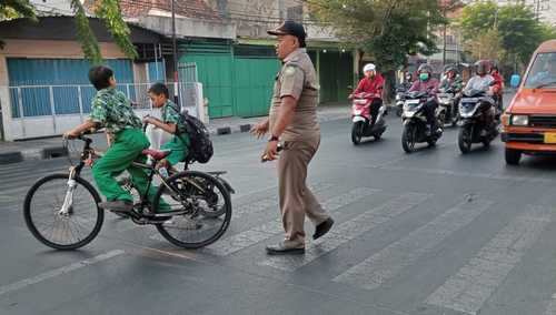 Rawan Kecelakaan, Anggota Linmas Satpol PP Sidoarjo Bantu Siswa SD Nyeberang Jalan Raya
